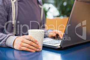 Young student using his laptop in cafe