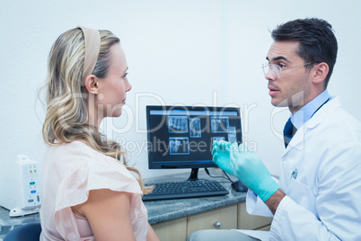 Dentist showing woman her mouth x-ray on computer