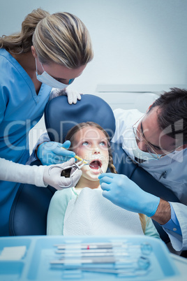 Dentist with assistant examining girls teeth