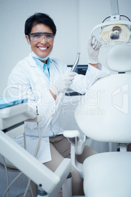 Smiling female dentist holding dental tool