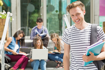 Handsome student smiling at camera outside