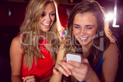 Pretty friends looking at smartphone together