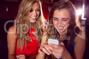 Pretty friends looking at smartphone together