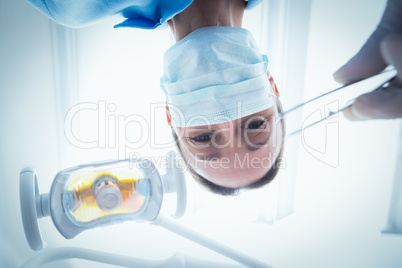 Female dentist in surgical mask holding dental tool