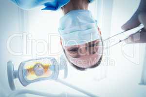 Female dentist in surgical mask holding dental tool
