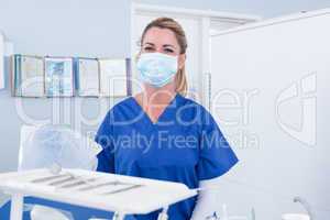 Dentist in mask behind tray of tools