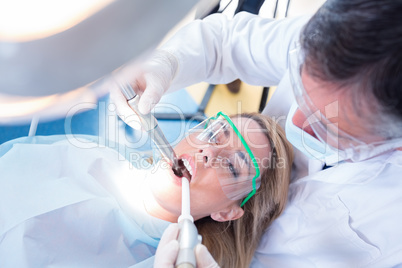 Dentist examining his patient with a suction hose