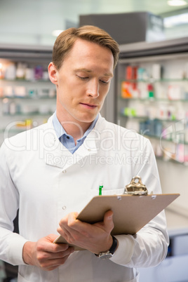 Focused pharmacist writing on clipboard Focused pharmacist writing on clipboard
