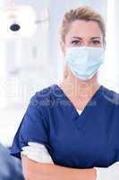 Dentist in mask looking at camera with arms crossed