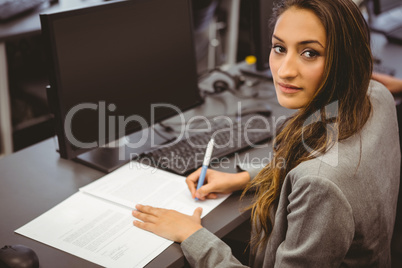 Smiling student sitting at desk writing on notepad