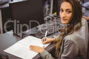 Smiling student sitting at desk writing on notepad