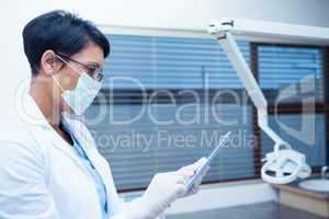 Dentist in surgical mask using digital tablet