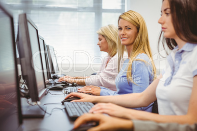 Happy woman in computer room smiling at camera