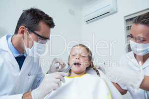 Dentist with assistant examining girls teeth