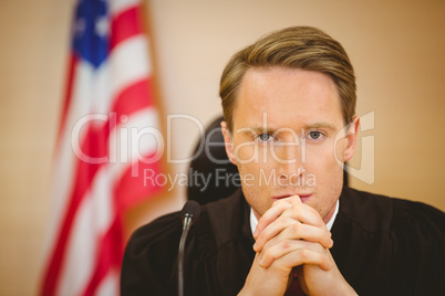 Portrait of a serious judge with american flag behind him