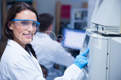 Smiling young chemist using the machine