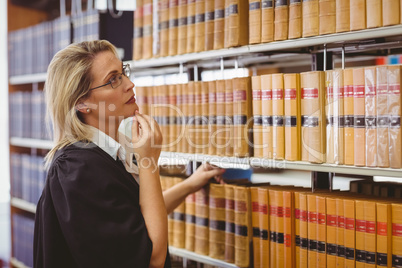 Lawyer wearing glasses and looking for a book in the shelf
