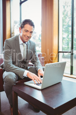 Smiling handsome businessman working at laptop