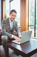 Smiling handsome businessman working at laptop