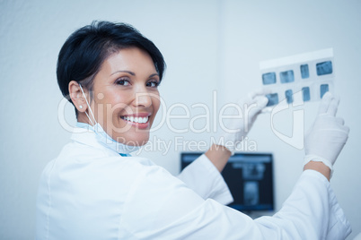 Smiling female dentist holding x-ray