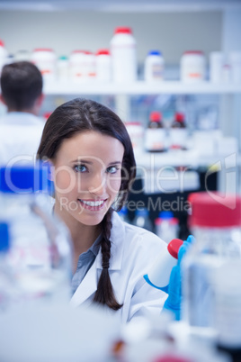 Smiling chemist picking up the bottles on the shelf