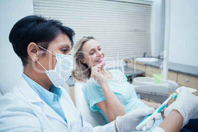 Dentist showing woman how to brush teeth