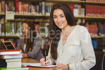 Smiling pretty brunette student writing in notepad