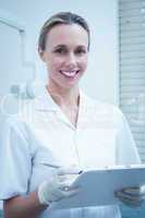 Smiling female dentist holding clipboard