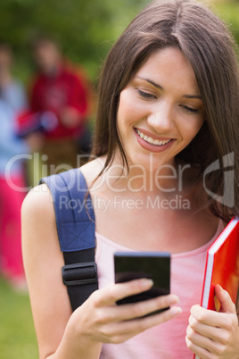 Pretty student sending a text outside on campus