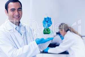 Science student holding green chemical in beaker