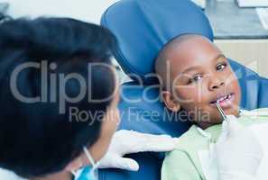 Dentist examining boys teeth in the dentists chair