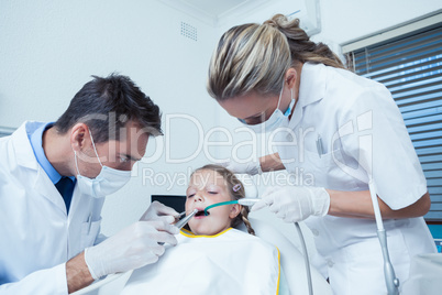 Male dentist  with assistant examining girls teeth