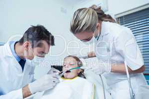 Male dentist  with assistant examining girls teeth
