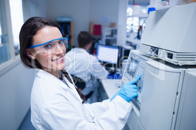 Smiling young chemist using the machine