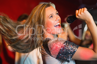 Happy blonde singing karaoke into mic