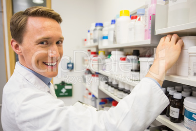 Handsome pharmacist taking medicine from shelf