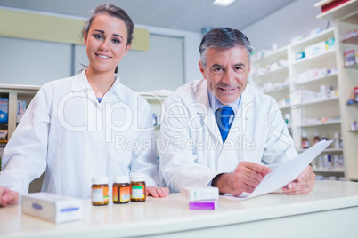 Pharmacist holding a prescription next to his trainee