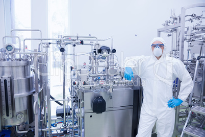 Scientist in protective suit leaning against machine