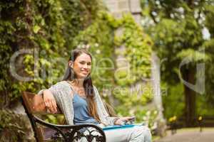 Smiling student sitting on bench holding her mobile phone