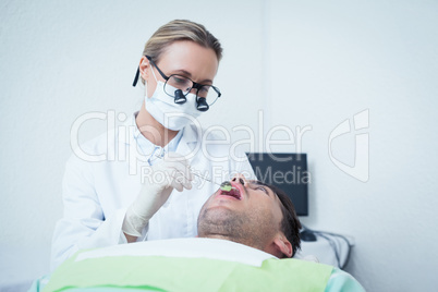 Female dentist examining mans teeth