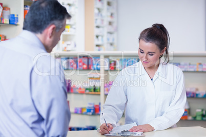 Trainee writing prescription in front of a customer