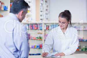 Trainee writing prescription in front of a customer