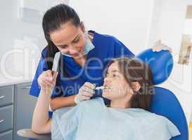 Pediatric dentist brushing teeth to her young patient