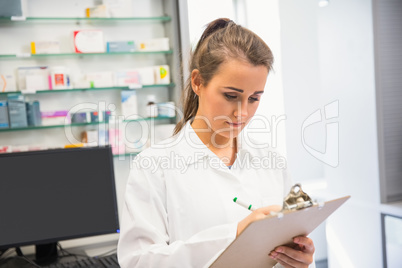 Junior pharmacist writing on clipboard