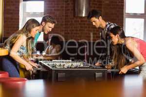 Smiling friends playing table football