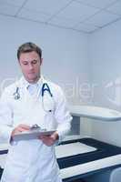 Doctor standing in front of the x-ray machine writing something