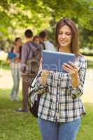 Smiling student with a shoulder bag and using tablet computer