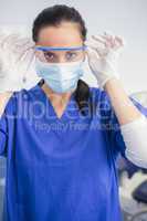 Dentist with surgical mask putting on her safety glasses