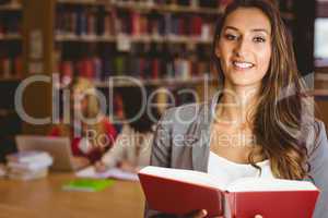 Smiling student holding a book and looking at camera