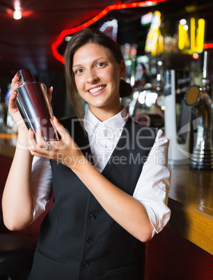 Happy barmaid smiling at camera making cocktail